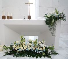 flowers and greenery sit on the floor in front of a white altar