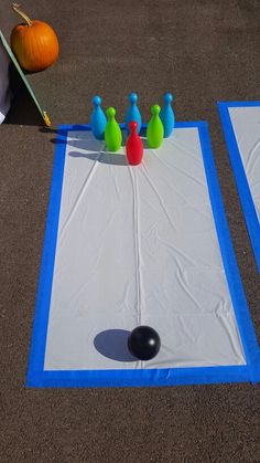 an outdoor game set up on the ground with bowling pins and balls in front of it