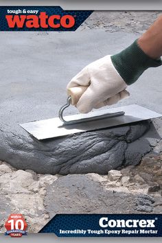 a person with gloves on holding a piece of metal in their hand over a rock