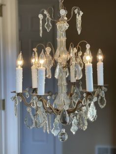 a chandelier hanging from the ceiling in a room with a door and window behind it