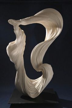 a white sculpture on a black surface with a dark back ground and the image is made up of wavy material