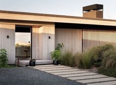 a modern house with an open door and steps leading up to the front porch area