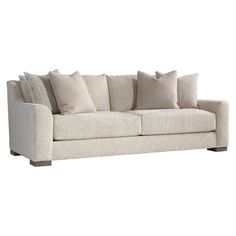 a white couch with many pillows on it's back and side ends, facing the camera