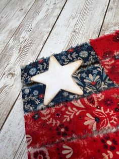 a wooden star on top of a red, white and blue quilted piece of cloth