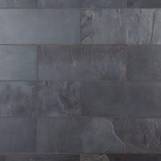 a black and white photo of a wall made out of slate tiles, with a vase in the middle