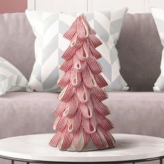 a pink christmas tree sitting on top of a white table next to a gray couch