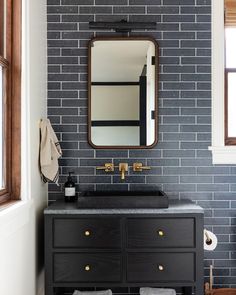 a bathroom with a black vanity and brick wall