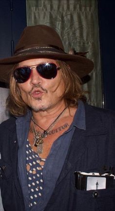 a man with long hair wearing a hat and sunglasses