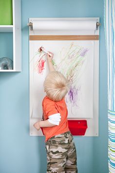 a young boy is painting on the wall