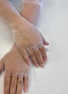 two hands with wedding rings on top of a white bed sheet and one holding the other's hand