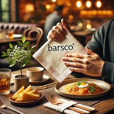 a person sitting at a table with food and drinks in front of him holding a napkin