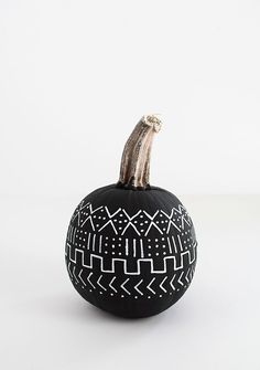 a black and white painted pumpkin with an animal on it's top, sitting against a white background