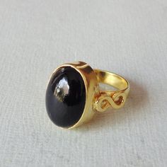 Unique in design, this bezel set statement ring is perfect as a Christmas gift. The handmade beauty with black onyx is a dark stunner. This single gemstone ring is made of brass furnished by 18k gold plating.Product DetailsItem Code: IAJBR- 1391Gross Wt. 7.00 GmsStone Name: Black OnyxMetal: 18K Yellow Gold Plated Over BrassRing Sizes: Please choose from drop down menu. If you do not see your finger size, select custom and I'll make a ring just for you! Shipping Info:All my items are safely and n Black Jewelry With Bezel Setting For Gift, Black Cabochon Ring As A Gift, Black Cabochon Ring For Gift, Onyx Cabochon Jewelry Gift, Black Onyx Ring Gold, Black Cabochon Ring In 14k Gold, Oval Cabochon Onyx Ring, Oval Cabochon Onyx Ring Gift, Black 14k Gold Cabochon Ring