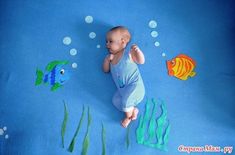 a baby laying on top of a blue blanket next to fish and seaweeds