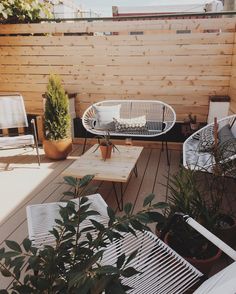 an outdoor patio with white wicker furniture and potted plants on the deck area