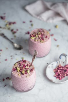 two desserts with pink frosting and sprinkles are on the table