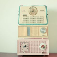 an old fashioned radio sitting on top of a wooden table next to a small clock