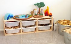 a wooden shelf filled with plastic containers and toy animals next to a metal pail