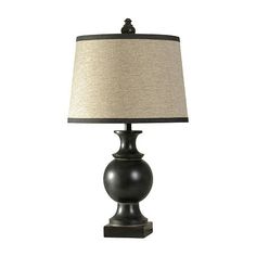 a black lamp with a beige shade on the base and a white linen lampshade