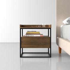 a nightstand with books on it next to a bed