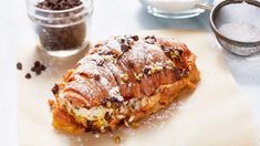 a pastry with chocolate chips and powdered sugar next to it on a cutting board