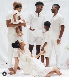 a group of people standing and sitting next to each other in front of a white backdrop