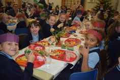 several children are sitting at a table with plates of food on it and smiling for the camera