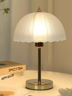 a white lamp sitting on top of a table next to a book