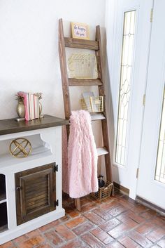 a white dog house with a pink coat on it's chest and shelf next to the door