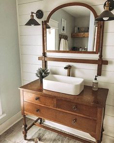 a bathroom sink sitting under a mirror next to a wooden dresser