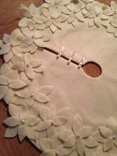 a piece of fabric with white flowers and pearls on it sitting on a wooden table