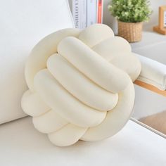 a white pillow sitting on top of a bed next to a book shelf and plant