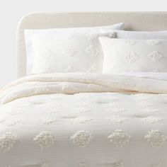 a bed with white comforters and pillows