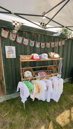 an outdoor clothing stand with clothes hanging from it's sides and on display in the grass