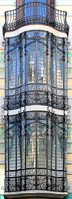 an ornate window on the side of a building with wrought iron railings and balconies