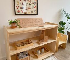 a wooden shelf with baskets and cups on it next to a potted plant in a room