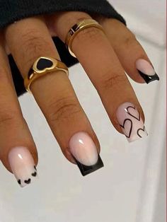 a woman's nails with black and white designs on them, including two gold rings