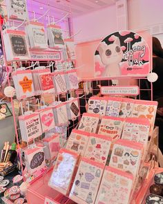 there are many cards on display in the store with pink lighting behind them and people looking at them