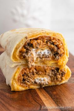 two burritos sitting on top of a wooden cutting board