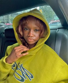 a young woman in a yellow hoodie sitting in the back seat of a car