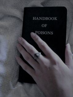 a person's hand on top of a book with the title handbook of poisons