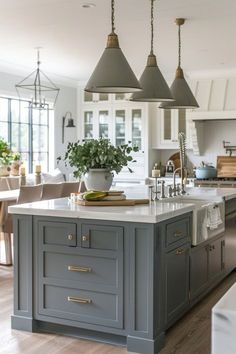 a large kitchen with an island in the middle and three lights hanging from the ceiling