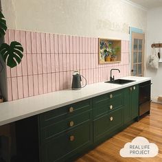 a kitchen with pink and green tiles on the wall, wooden flooring and cabinets