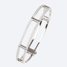 An elegant and modern bangle bracelet with a dusting of sparkling white diamonds along its lateral bars. 18K white gold locking cage bangle bracelet with white diamonds on lateral bars (1.2 tcw) 7.0” internal circumference 0.63” wide Luxury Diamond White Diamond Bangle, Modern White Gold Diamond Bracelet Channel Set, Modern Channel Set Diamond Bracelet In White Gold, Modern Diamond Bangle Bracelet With Prong Setting, Modern Diamond Bangle With Pave Setting, Elegant White Gold Bangle With Channel Set, Modern White Gold Bracelets With Channel Set, Modern White Gold Bracelets Channel Set, Elegant White Gold Channel Set Bangle