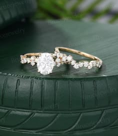 two diamond rings sitting on top of a green car tire, with leaves in the background