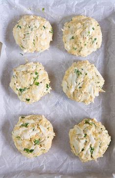 six biscuits with different toppings sitting on wax paper