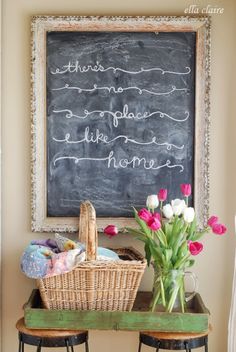 two stools with flowers in front of a chalkboard that says there's no place like home