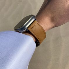 an apple watch on someone's wrist wearing a tan leather band and silver case