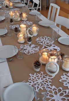 a long table with white plates and candles on it