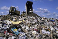 a pile of garbage with a bulldozer in the background